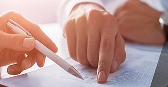 a hand pointing at paper with pen