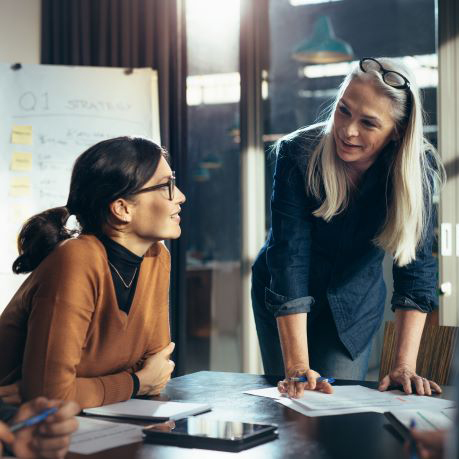 Two female colleagues chatting at conference table