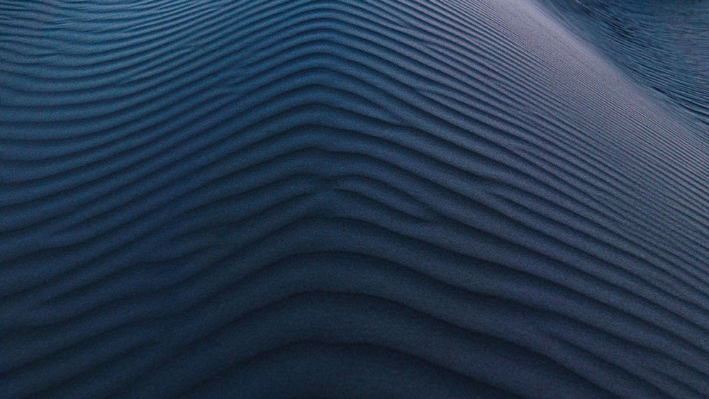 Stock image of desert sands at night with deep blues and teals.