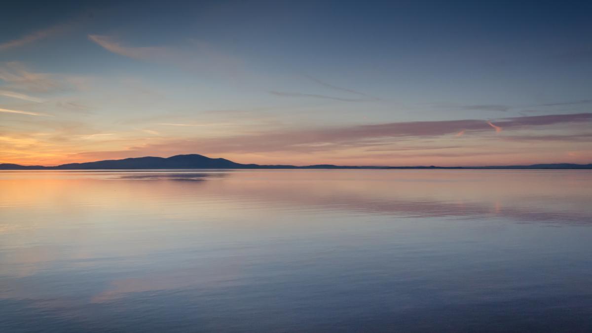 Lake view at sunset with clouds and mountains in background