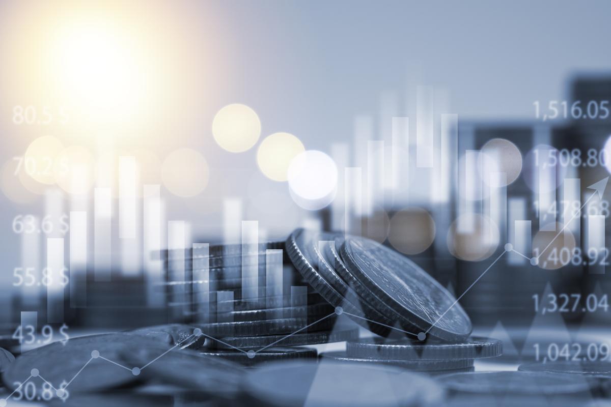 Composite image of coins in foreground, bar graph in background with sunlight on left and reflection of cityscape