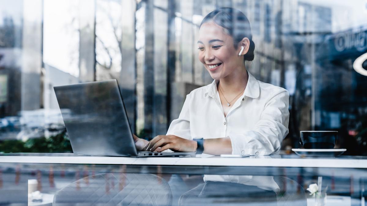 Young woman drinking coffee and using laptop at a cafe