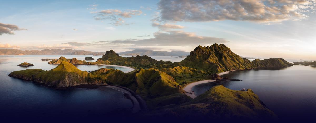 Adobe stock aerial photography of a nature landscape containing an island with mountains and a cloudy blue sky.