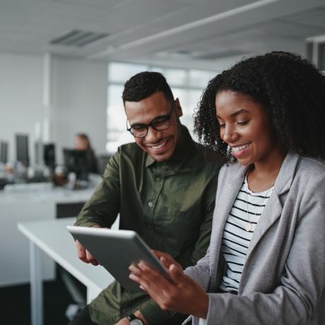 two people sitting on a desk viewing tablet