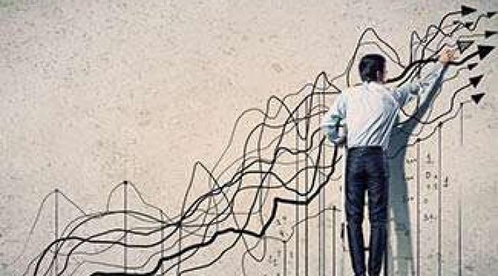 A generic image of a man drawing upwards stock lines on the wall.