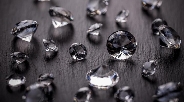 Handful of diamonds scattered on a black wooden surface