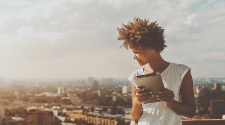 Woman standing with a tablet, overlooking a city