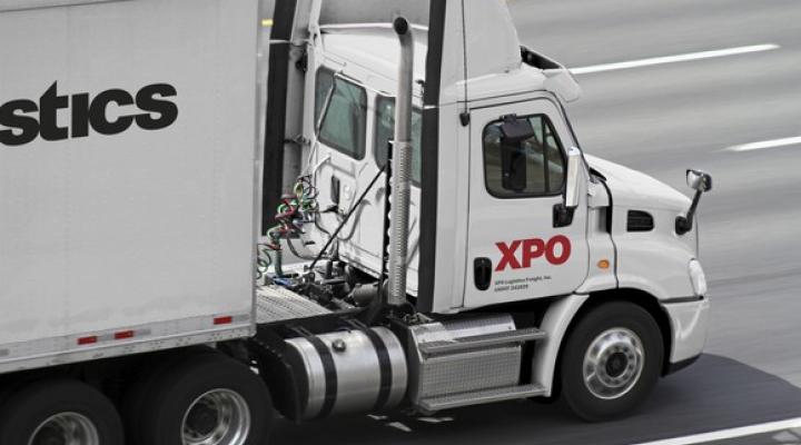 White semi tractor-trailer with XPO logo on it, driving down a four-lane highway.