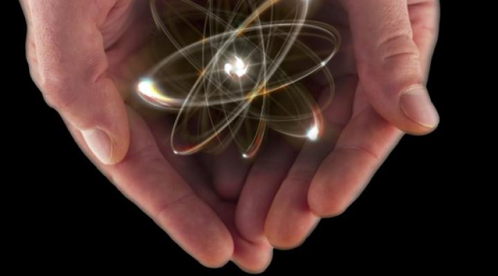 A visualization of an atom in a pair of cupped hands.