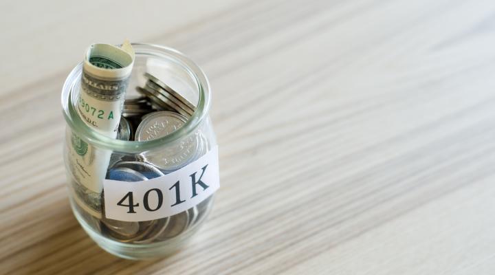 Glass jar labeled 401K stuffed with bills and coins.