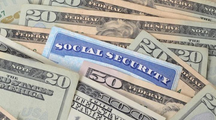 Blue Social Security card sticking out of a pile of U.S. currency.