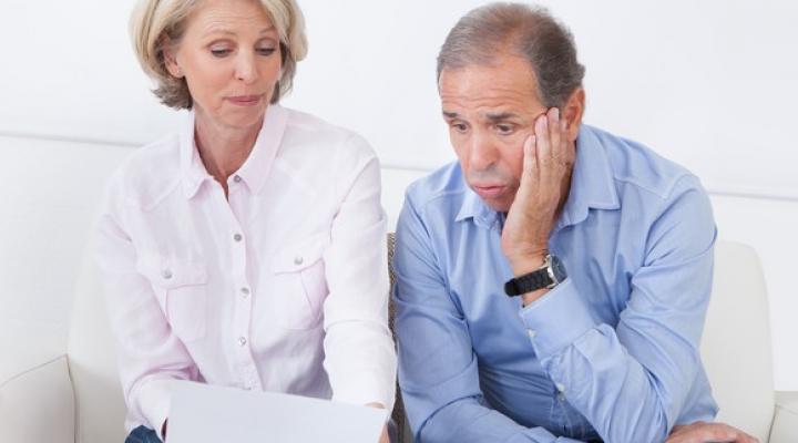 Older Couple Worried While Looking At Bills Paperwork Getty