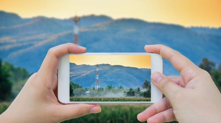 A person taking a picture of a cell tower with their mobile phone.