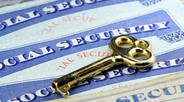 Social Security cards on a table with a gold key lying on top.