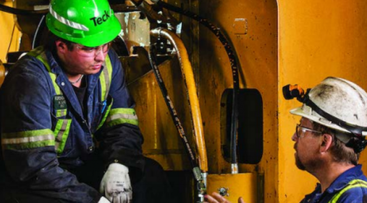 Teck employees talking on mining equipment.