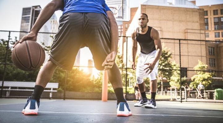 Two young men playing basketball outside