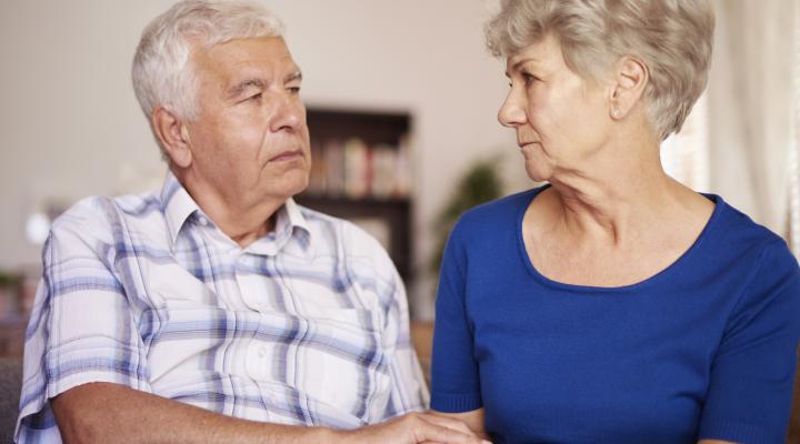 Senior couple with serious expressions holding hands