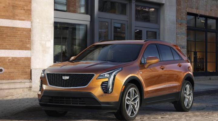 A copper-colored Cadillac XT4, a small crossover SUV, parked on a city street.