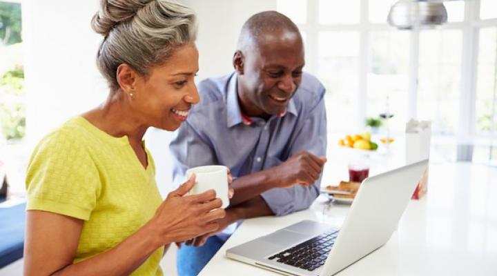 Mature couple smiling and looking at laptop