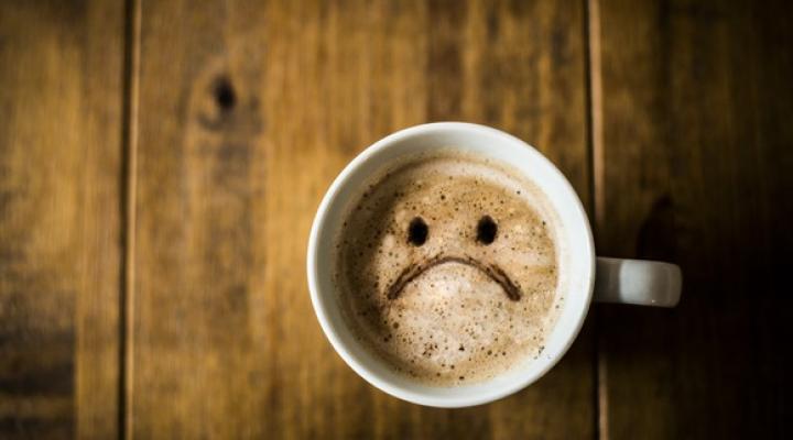 A sad looking Coffee Cup on a brown rustic table.