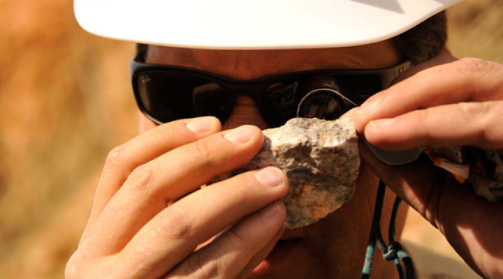 An image of a Hecla Mining employee examining a rock.