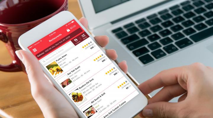 A man holds a smartphone with the Grubhub app open.