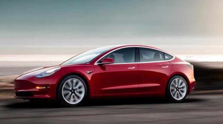 A red Tesla Model 3, a compact luxury spots sedan.