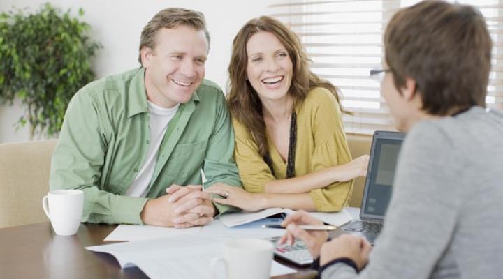 Smiling couple sitting across a desk from a professional.