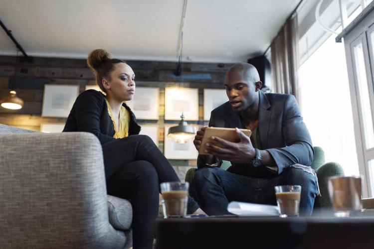 A man holding a tablet and a woman have a conversation